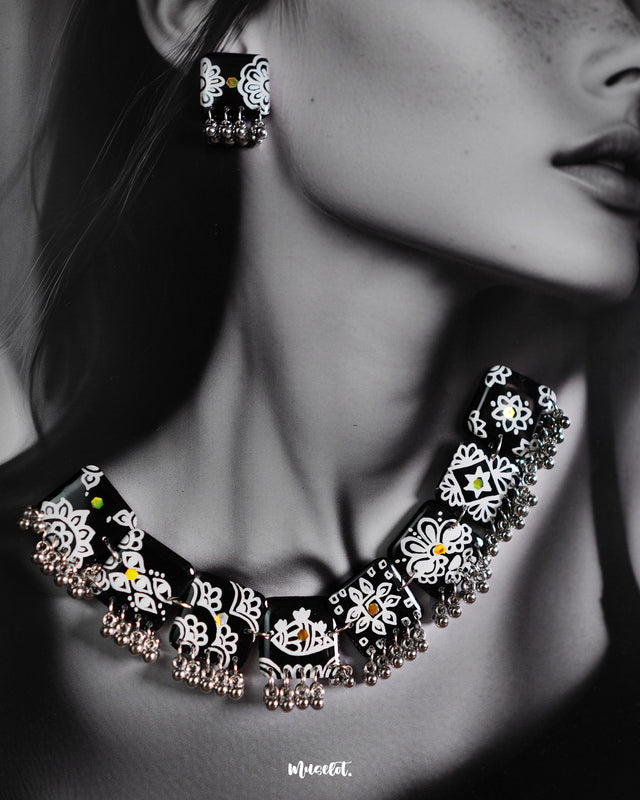 Shabnoor black floral jewelry set featuring intricately crafted earrings and a matching necklace, adorned with hand-painted floral motifs in deep black and silver, celebrating artisanal charm and understated elegance — Muselot.