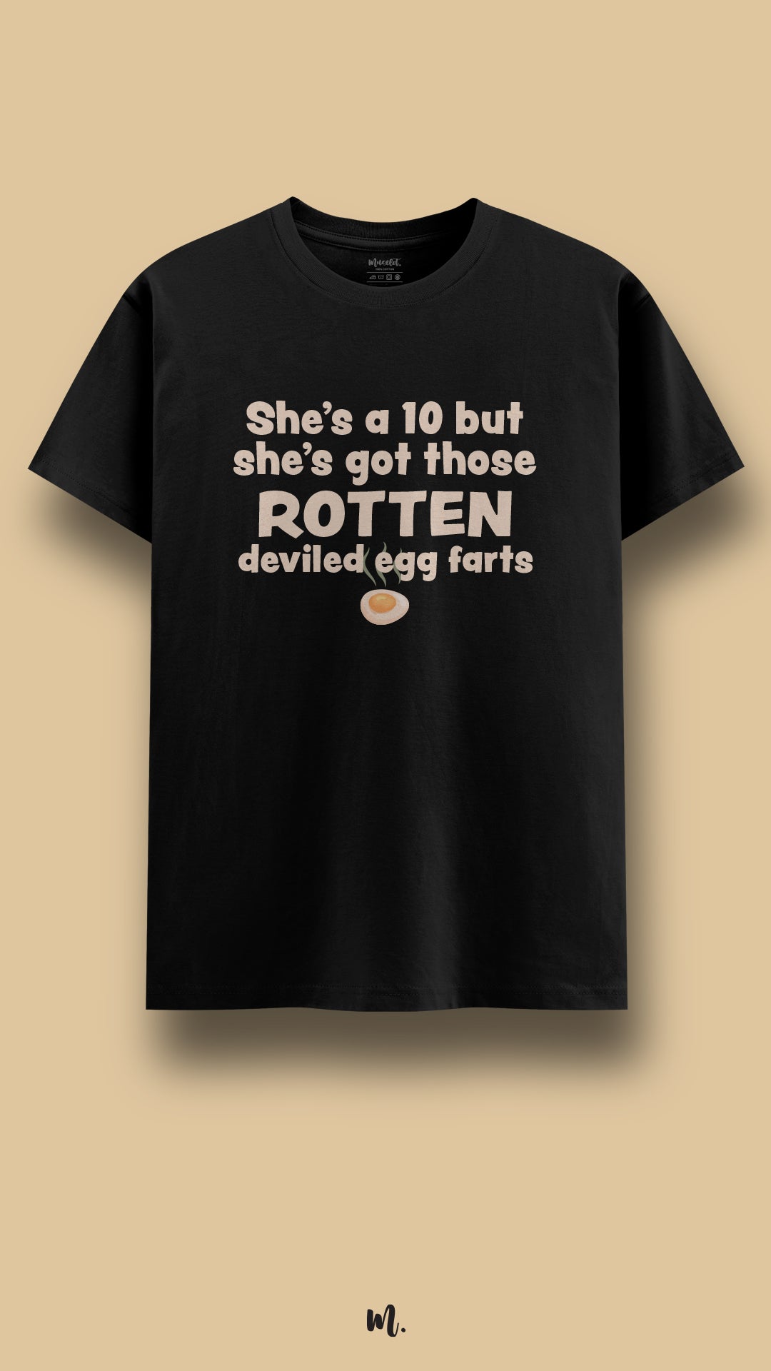Black graphic t-shirt showcasing the statement “She’s a 10 but she’s got those ROTTEN deviled egg farts” in bold beige typography with a small egg illustration, highlighting an sarcastic and attention-grabbing humor vibe against a clean beige background – Muselot