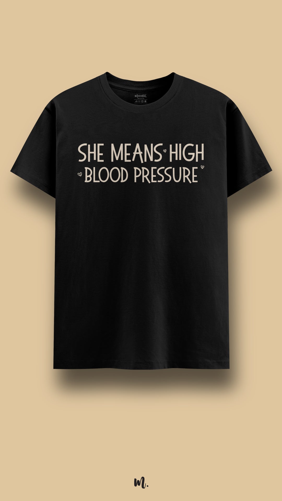 Black graphic t-shirt showcasing the statement “She Means High Blood Pressure” in clean beige typography with subtle heart accents, highlighting a sarcastic yet affectionate couple joke against a neutral beige background – Muselot