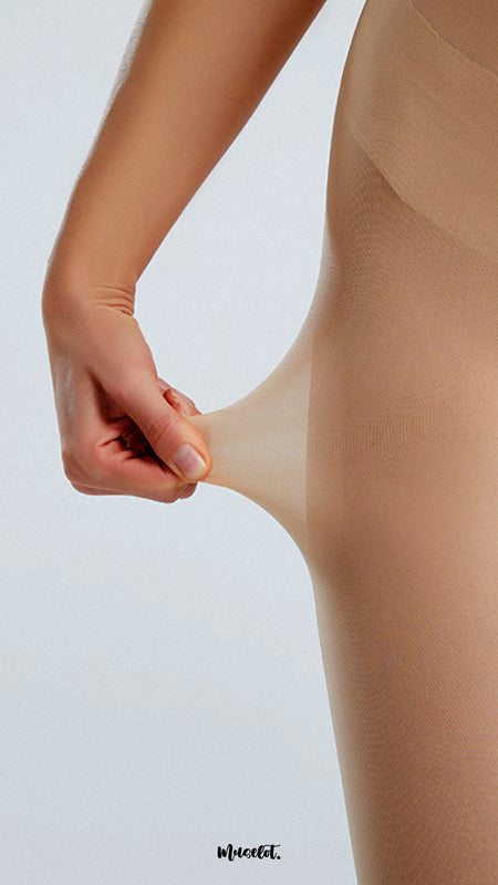 A model, wearing Silken Touch Premium Skin Sheer Pantyhose, is stretching the fabric to showcase its durable, tear-resistant design. The sheer skin tone fabric highlights a smooth, flawless finish, offering both strength and elegance for everyday wear. -Muselot