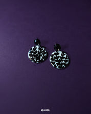 Siyahgul black floral stud earrings, elegantly set against a deep purple background, with intricate floral detailing and a sleek black finish that captures a perfect balance of drama and sophistication — Muselot.