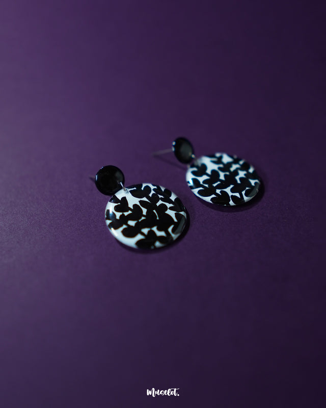 Siyahgul black floral stud earrings, set against a deep purple background, with finely crafted floral details and a striking black tone that evoke a sense of bold, artistic elegance — Muselot.