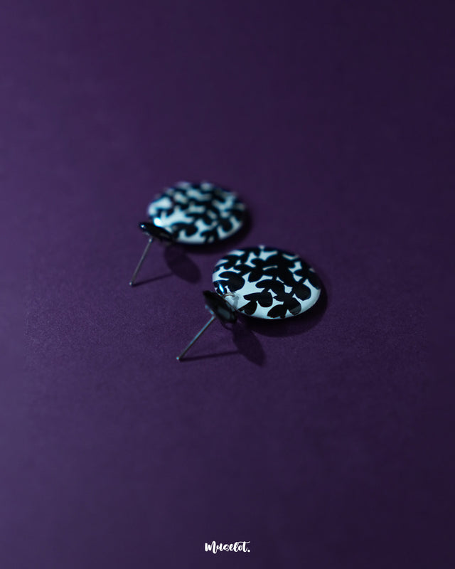 Siyahgul black floral stud earrings, highlighted against a rich purple background, with delicate floral detailing and a deep black hue that bring out their striking elegance and bold charm — Muselot.