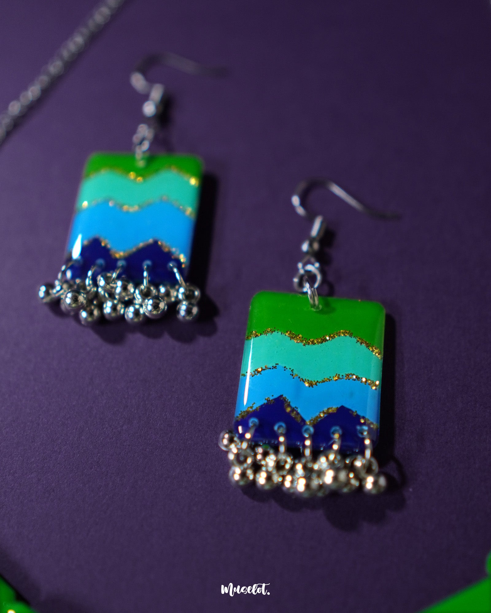 A zoomed-in shot of the Sukoon waterfall boho earrings, highlighting the intricate silver-toned chainwork and enamel detailing in soft green and blue hues. The close-up showcases the fine craftsmanship and bohemian charm — Muselot.