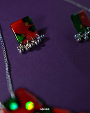 The Surkhbaagh handmade jewelry set displayed elegantly — featuring oxidized silver earrings and a matching pendant adorned with maroon beads and intricate mirror work, capturing the essence of traditional craftsmanship — Muselot.
