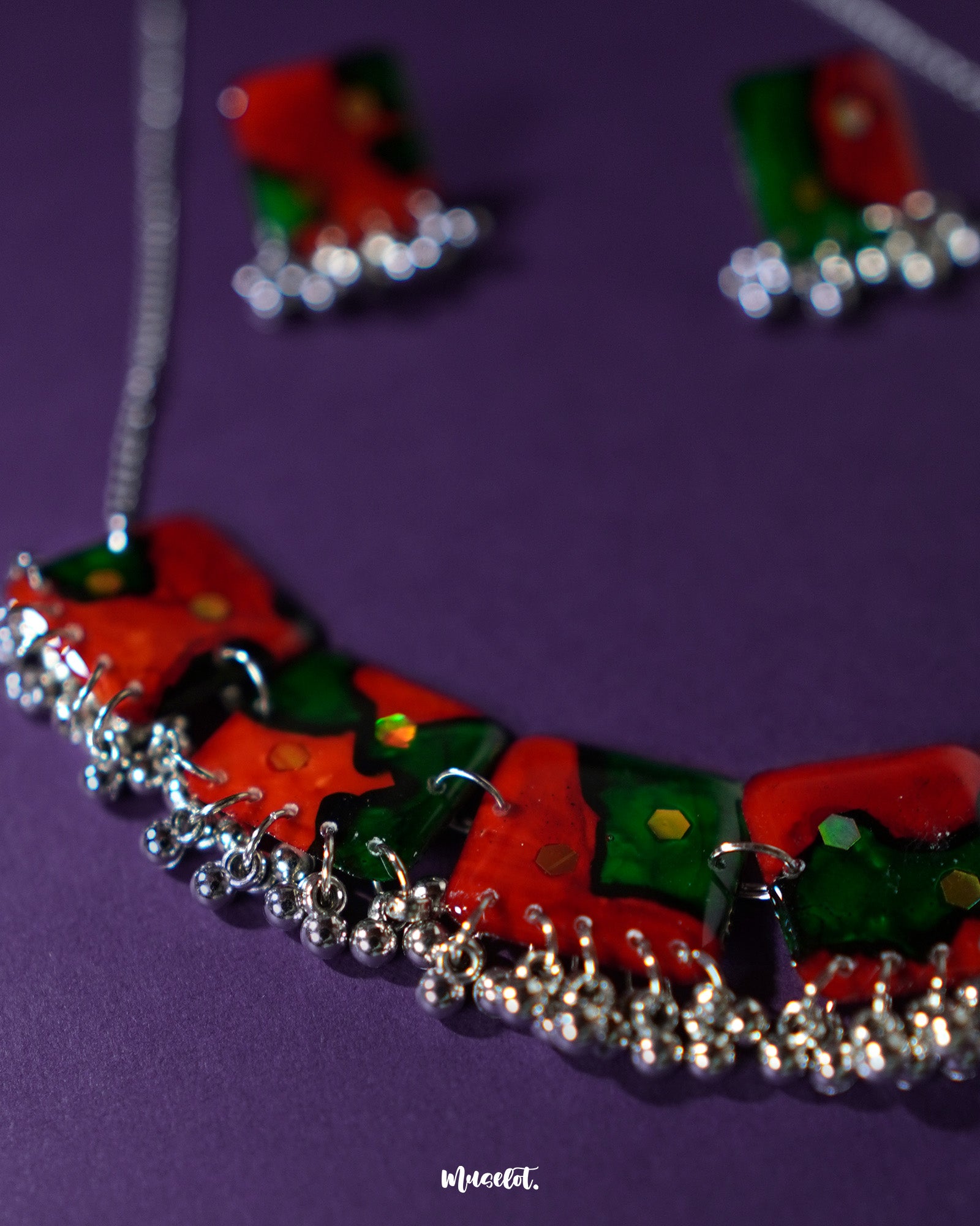 Flatlay of the Surkhbaagh handmade jewelry set featuring a statement choker and matching earrings adorned with mirror work, oxidized silver finish, and maroon beads, celebrating rich ethnic artistry — Muselot.