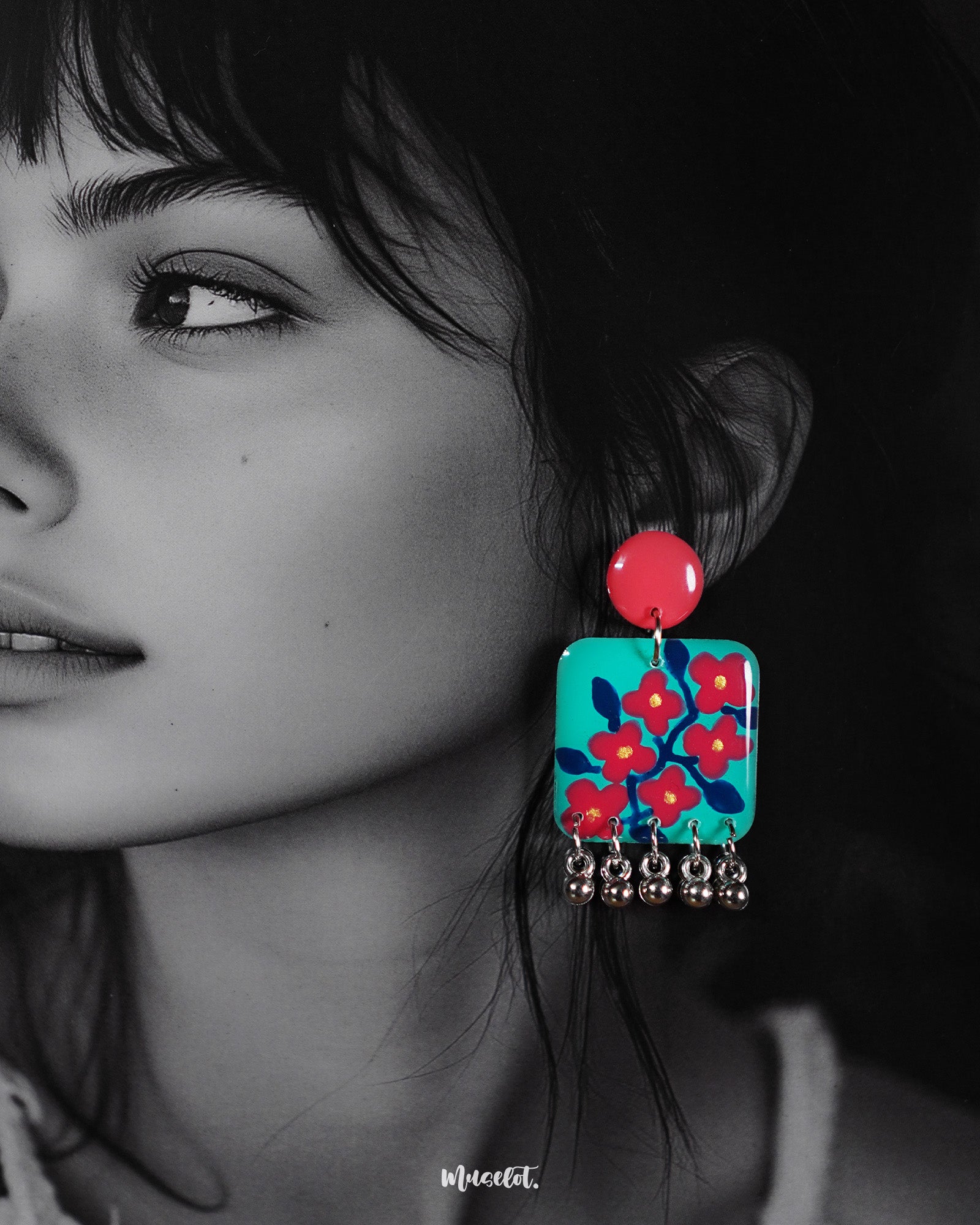 Close-up of a woman wearing the Surkhili floral earrings, highlighting the intricate hand-painted red flowers on a turquoise base and the delicate silver ghungroo drops that add movement and charm — Muselot.