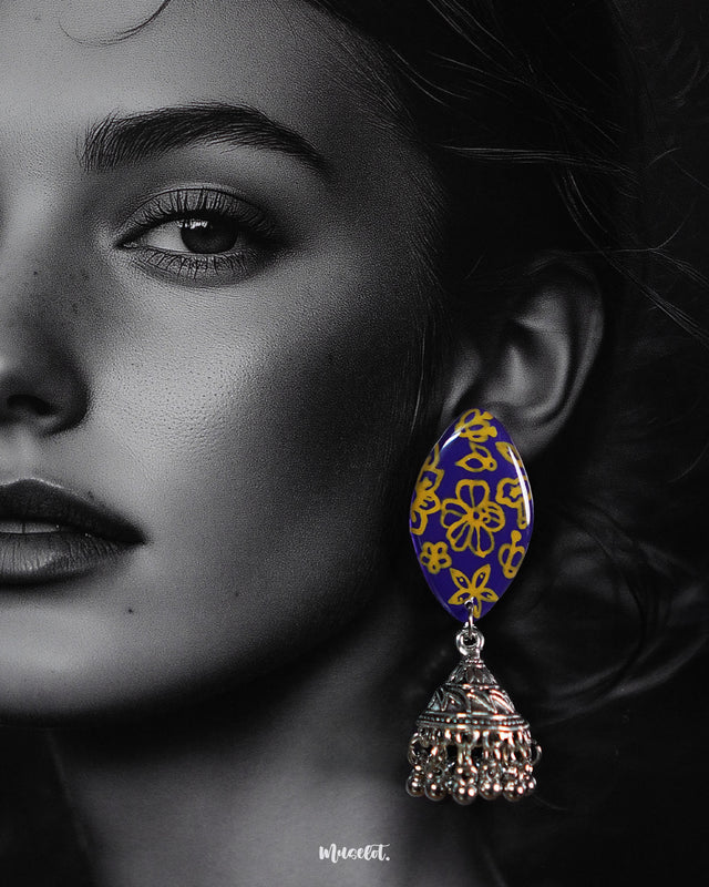 A close-up view of the Tabeer floral jhumkas highlighting their ornate floral domes and finely detailed craftsmanship. The soft lighting accentuates the delicate textures, bringing out the charm and elegance of these timeless earrings — Muselot.