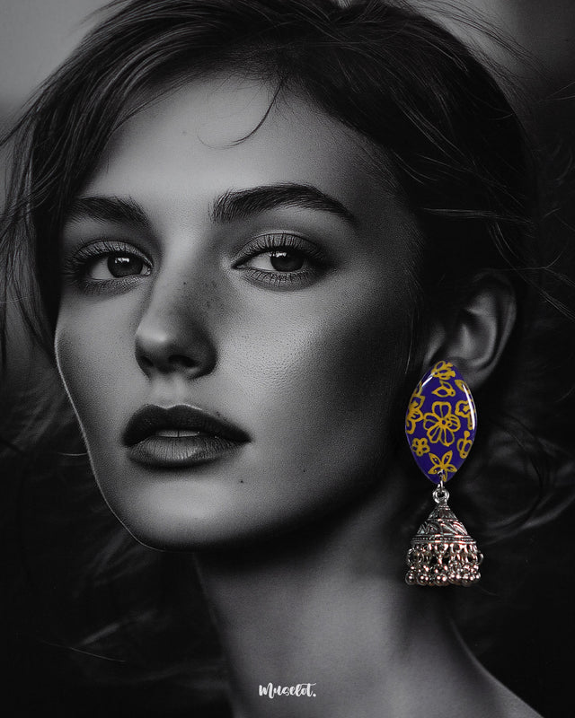 The model is wearing the Tabeer floral jhumkas, gracefully showcasing their intricately designed floral domes and charming danglers. The warm tones and delicate detailing enhance the earrings’ traditional elegance, making them a stunning addition to any festive attire — Muselot.