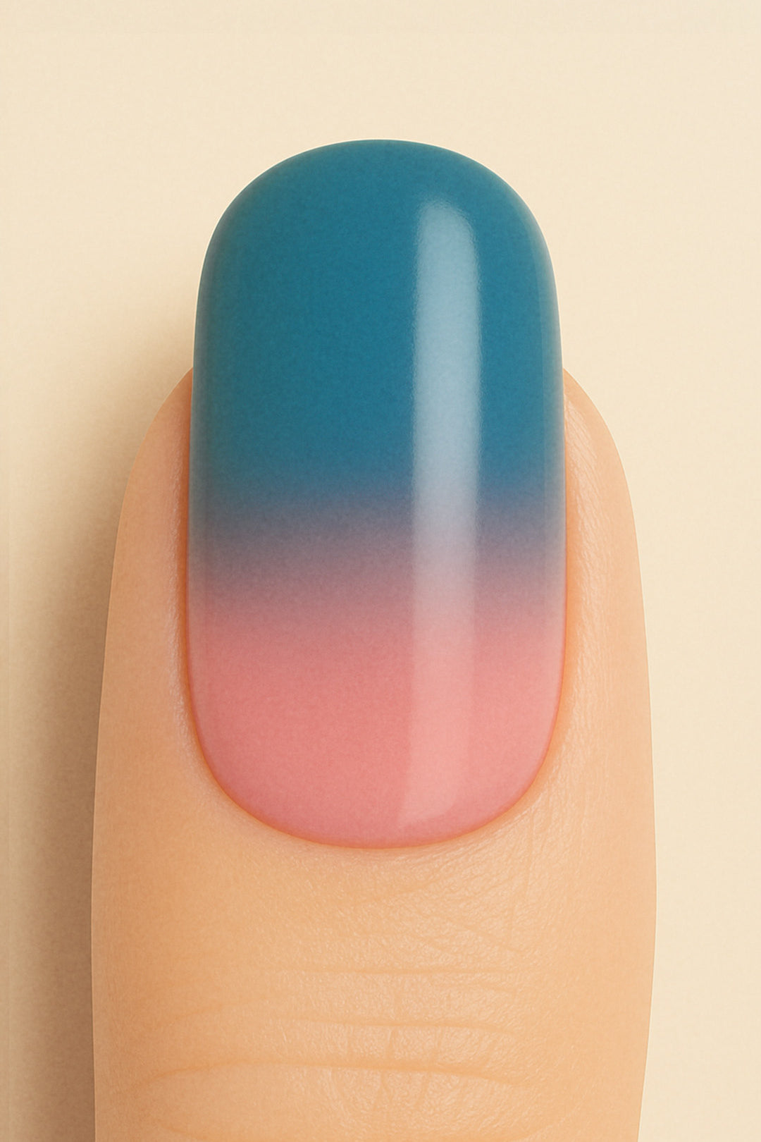 A close-up shot of a model’s finger wearing Twilight Rose Ombre nail stickies, showcasing the seamless transition from a muted rose pink at the base to a deep teal-blue at the tip, highlighting the modern elegance and smooth glossy finish of gradient nail art – Muselot.