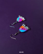 Ufaq multicolor hook earrings, set against a rich purple background, with vibrant colors and geometric patterns that bring out the earrings' bold yet refined elegance — Muselot.