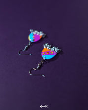 Ufaq multicolor hook earrings, set against a rich purple background, featuring a burst of colors and unique geometric shapes that highlight the earrings' lively and sophisticated charm — Muselot.