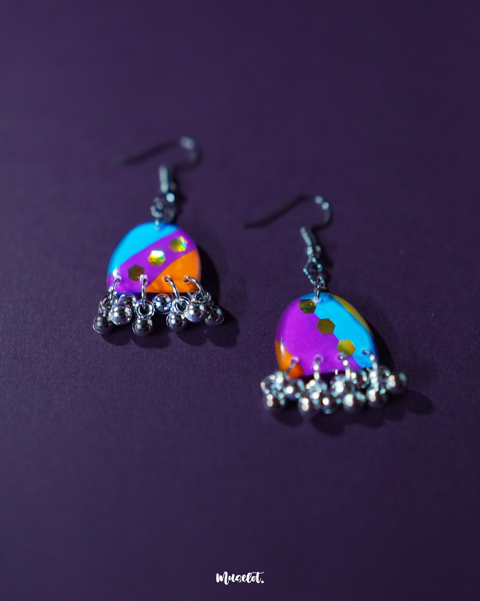 Ufaq multicolor hook earrings, showcased against a rich purple background, with a blend of vibrant colors and geometric designs that highlight their playful and sophisticated charm — Muselot.