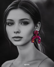 Model wearing Ulfat glitter resin stud earrings in bold pink-purple sparkle, styled to showcase their statement arch design and vibrant shine – Muselot.