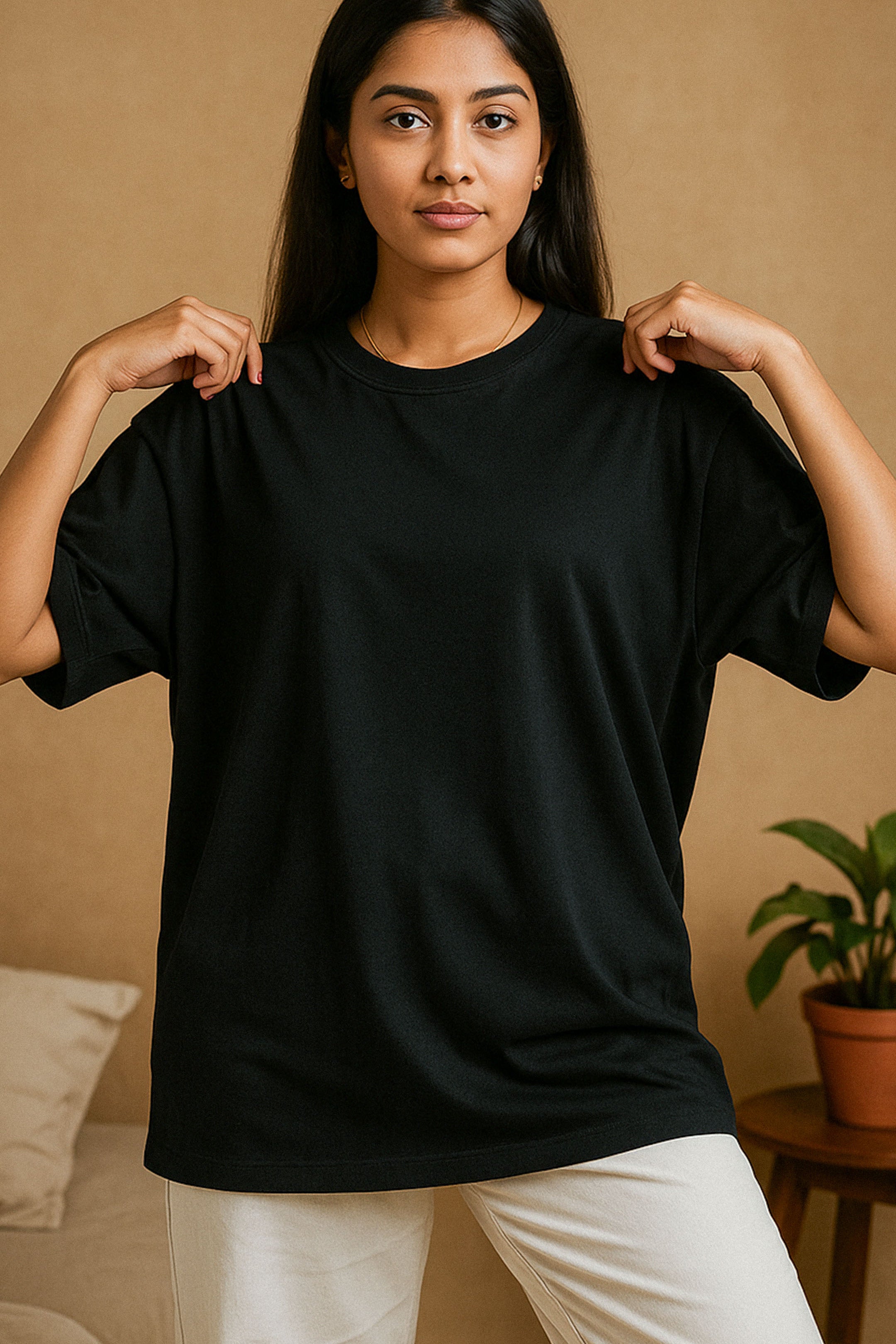 A model wearing a unisex oversized black T-shirt gently adjusting the collar, showcasing the minimal lifestyle appeal and effortless charm of this versatile wardrobe essential tee for an everyday wear — Muselot.