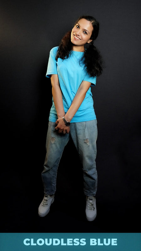A happy model wearing a unisex stretchable t shirt, looking at the camera with her head bent sideways, holding her hands together, highlighting a relaxed casual fit-Muselot