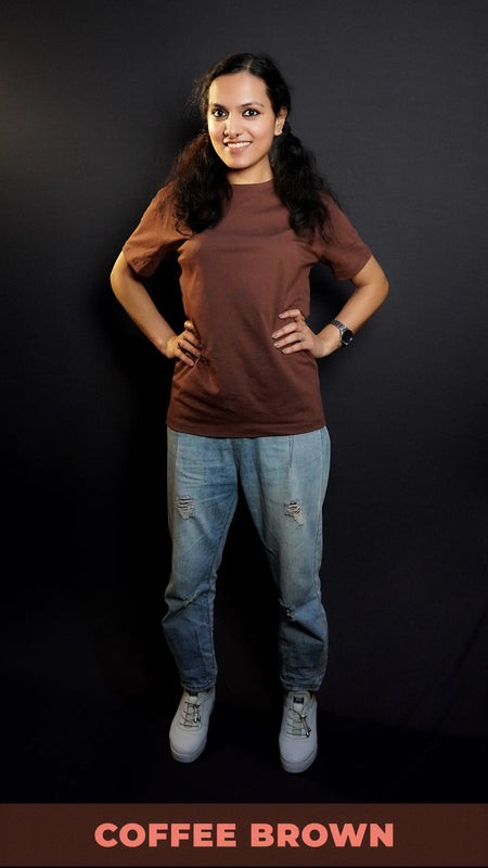 A model wearing a long plain round neck coffee brown t-shirt, posing with her hands on the sides of her waist, showcasing a flowing voguish style-Muselot