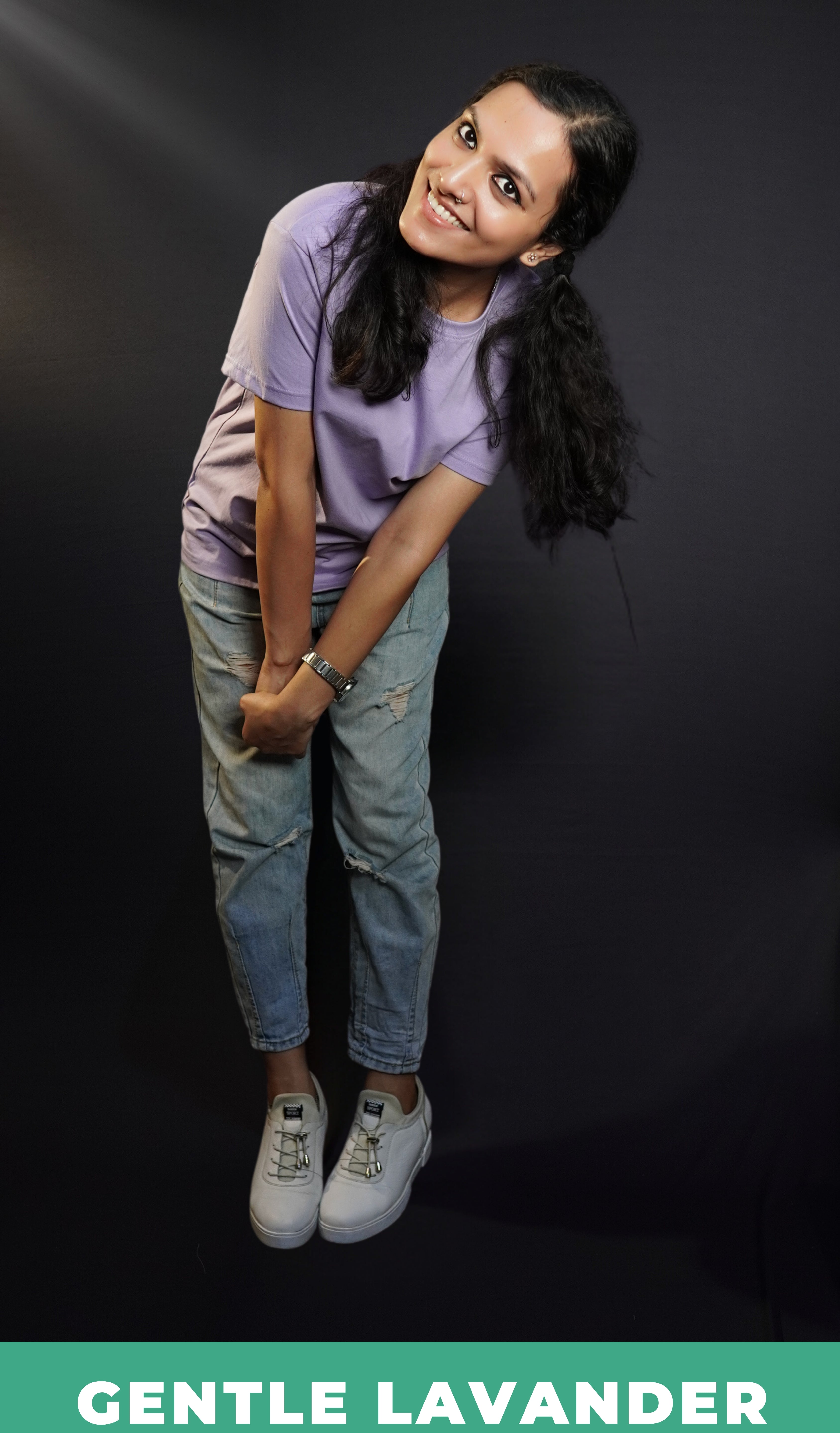 A woman smiling brightly wearing a short sleeved long length women's t-shirt, posing as she bends forward with her hands grabbing each other, highlighting a funky cool style-Muselot