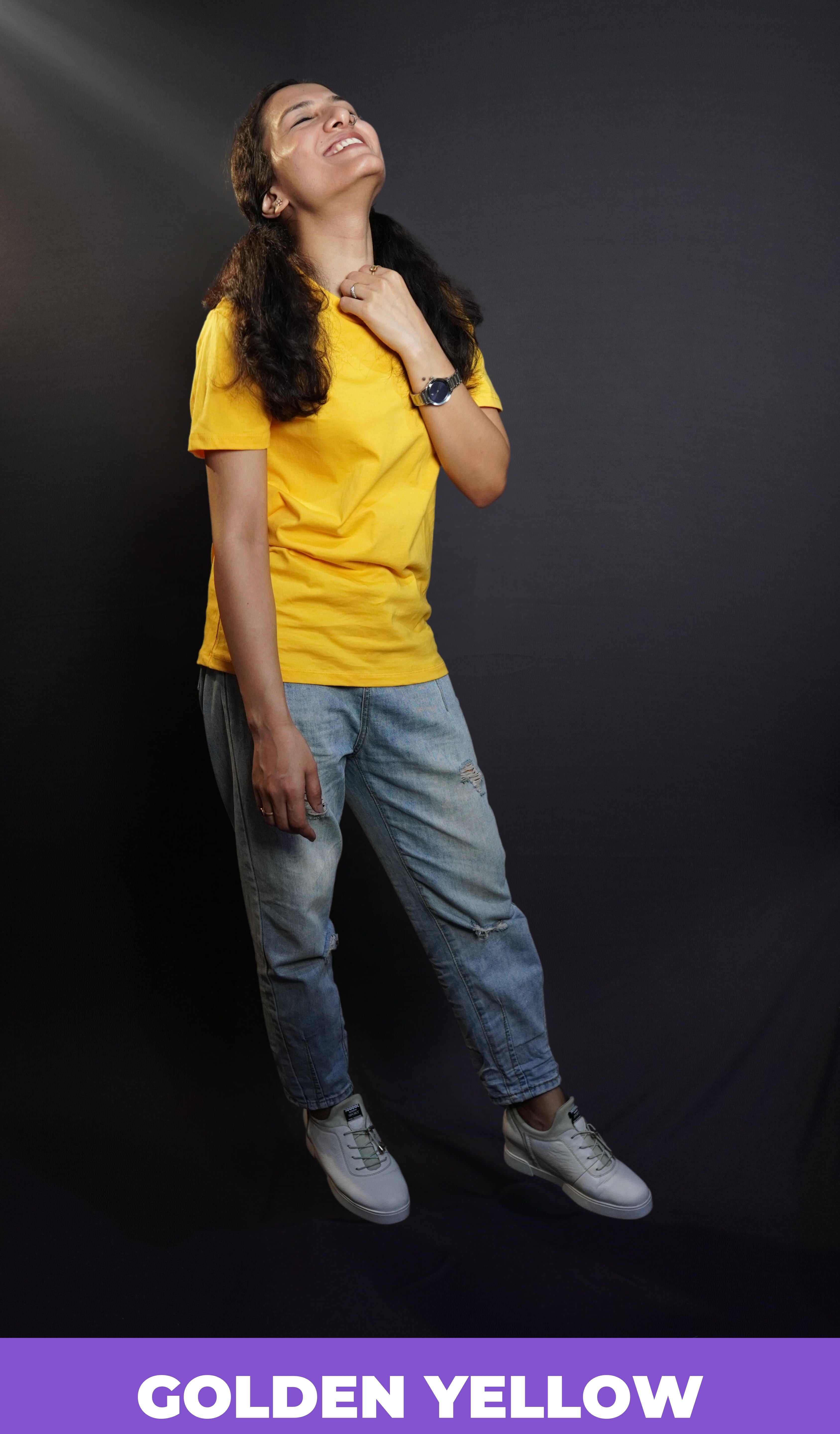 A happy woman in a casual cotton round neck short sleeved golden yellow plain T shirt paired with blue jeans and comfortable shoes-Muselot