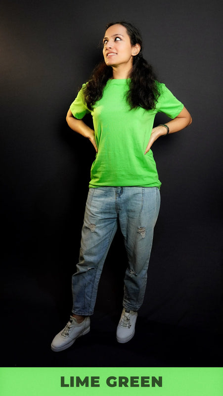 A stylish model posing with her hands on her sides looking sideways, wearing a lime green cotton long length adult's t-shirt, highlighting a trendy snug fit-Muselot