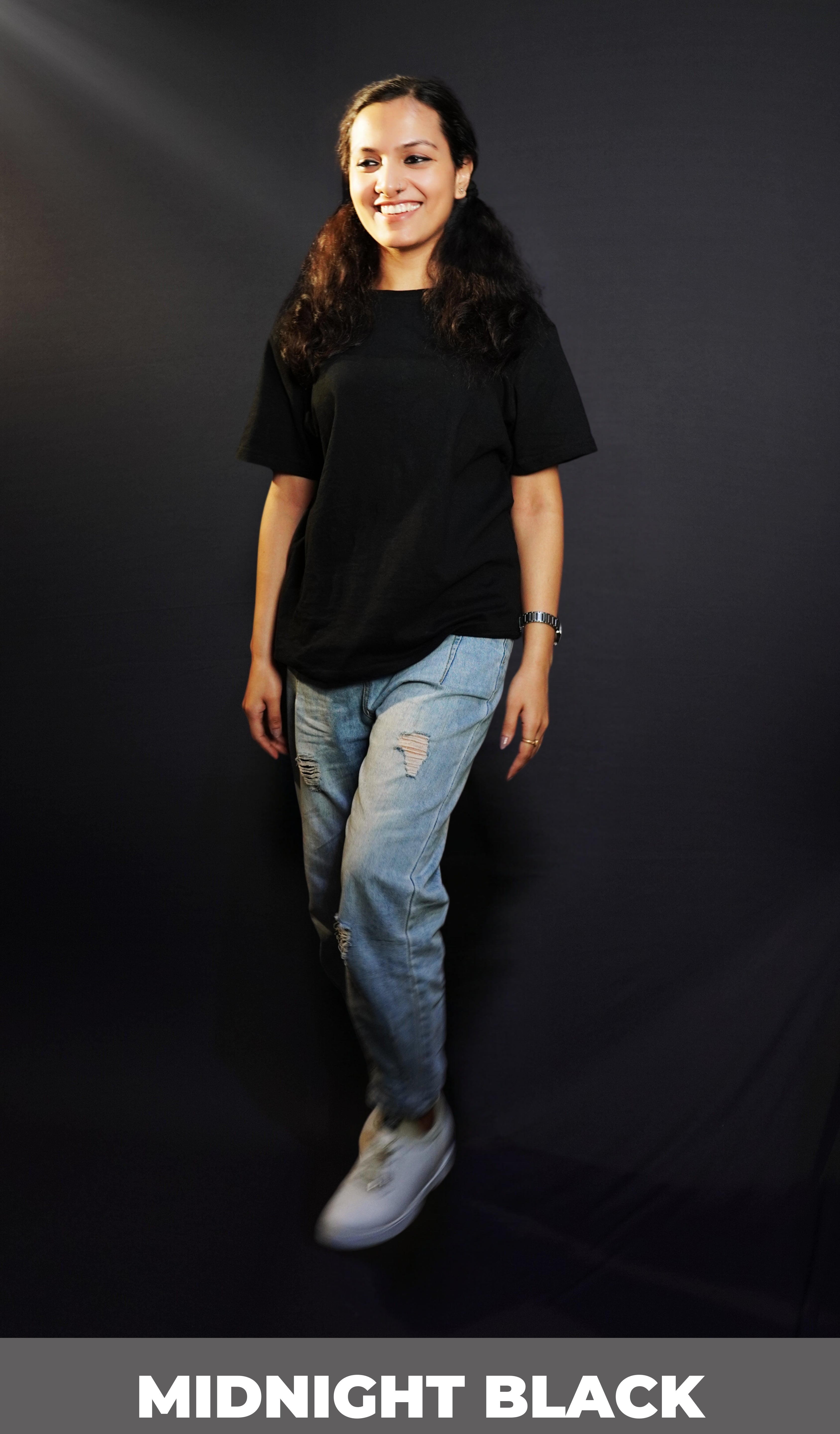 A woman walking casually against a dark background, wearing a men's round neck stretchable plain midnight black cotton t-shirt, showcasing a everyday cozy fit-Muselot