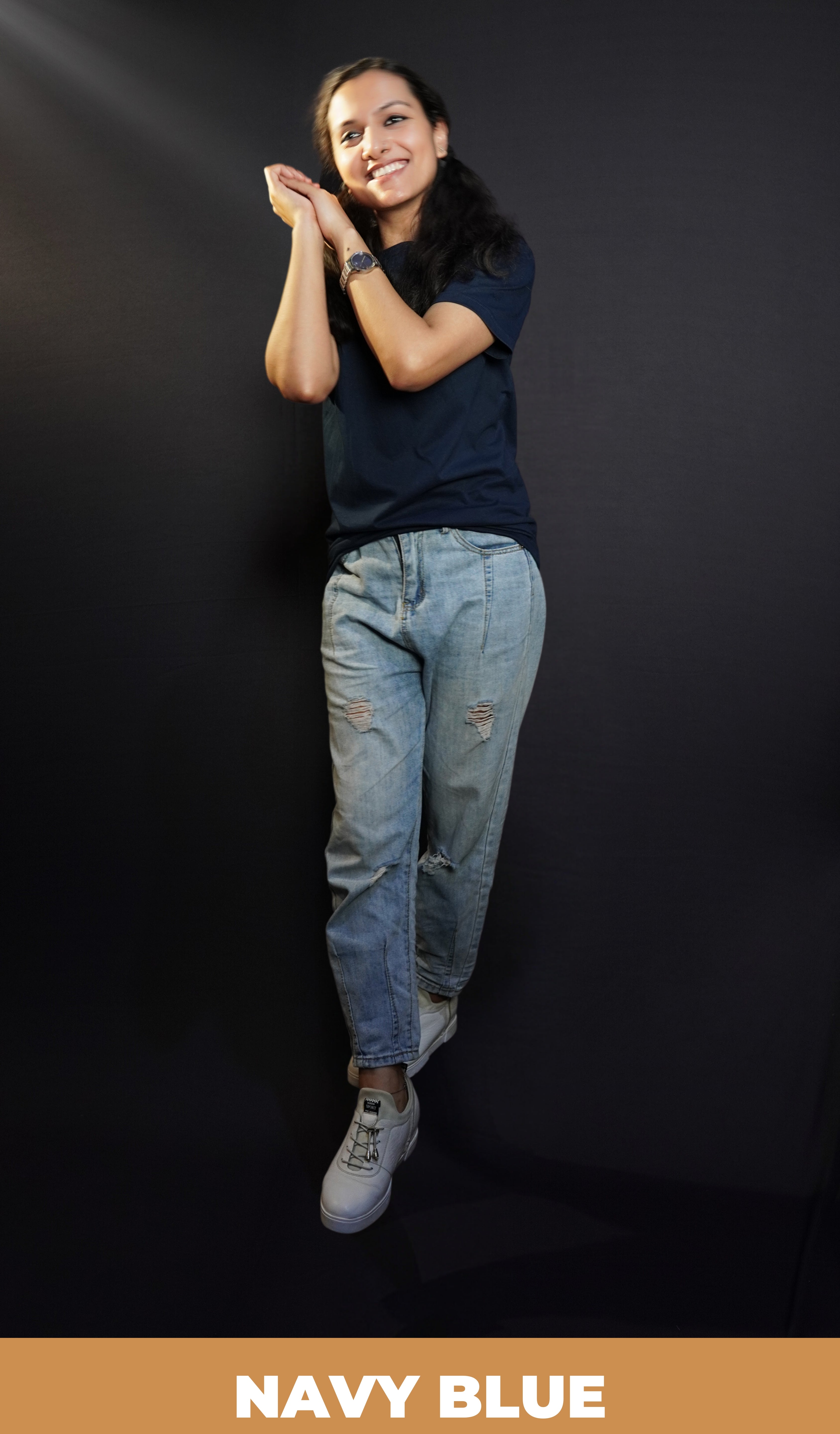 A woman wearing a cotton round neck short sleeved moisture wicking navy blue t-shirt, posing with her palms hugging each other near her head, showcasing a modish in vague look-Muselot