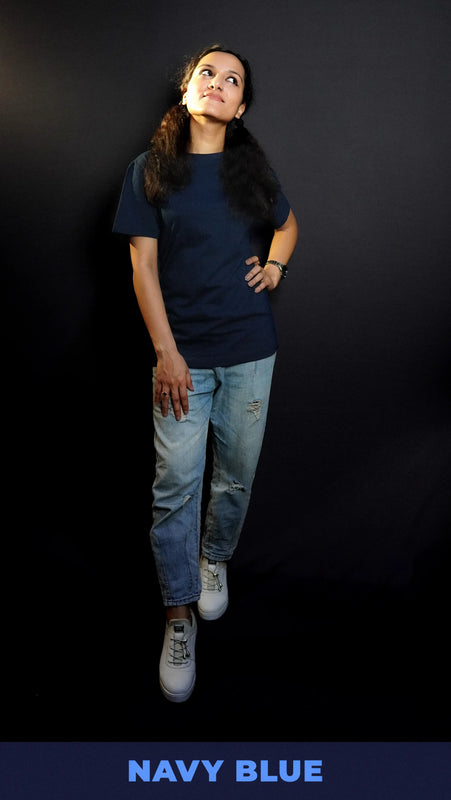 An elegant model wearing a unisex cotton round neck stretchable plain navy blue t-shirt, posing with her hand on her waist and other on her thigh as she looks sideways with her chin up high, showcasing a popular modish look-Muselot