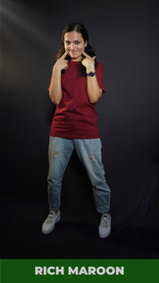 A woman smiling as her fingers poke into her cheeks, wearing a women's long length summer rich maroon t-shirt, showcasing a fashionable stylish look-Muselot