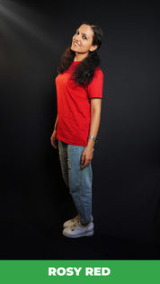 A woman standing sideways as her head bends slightly to the camera, smile on her lips, wearing a cotton round neck moisture wicking short sleeved rosy red t-shirt, highlighting a modish loose fit-Muselot