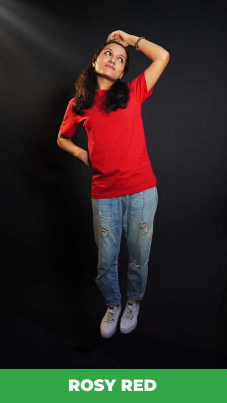 A woman wearing a unisex cotton long length stretchable rosy red t-shirt, posing with her hand on her head and other behind her waist looking sideways with her head up and bent slightly to her side, showcasing a trendy casual fit-Muselot