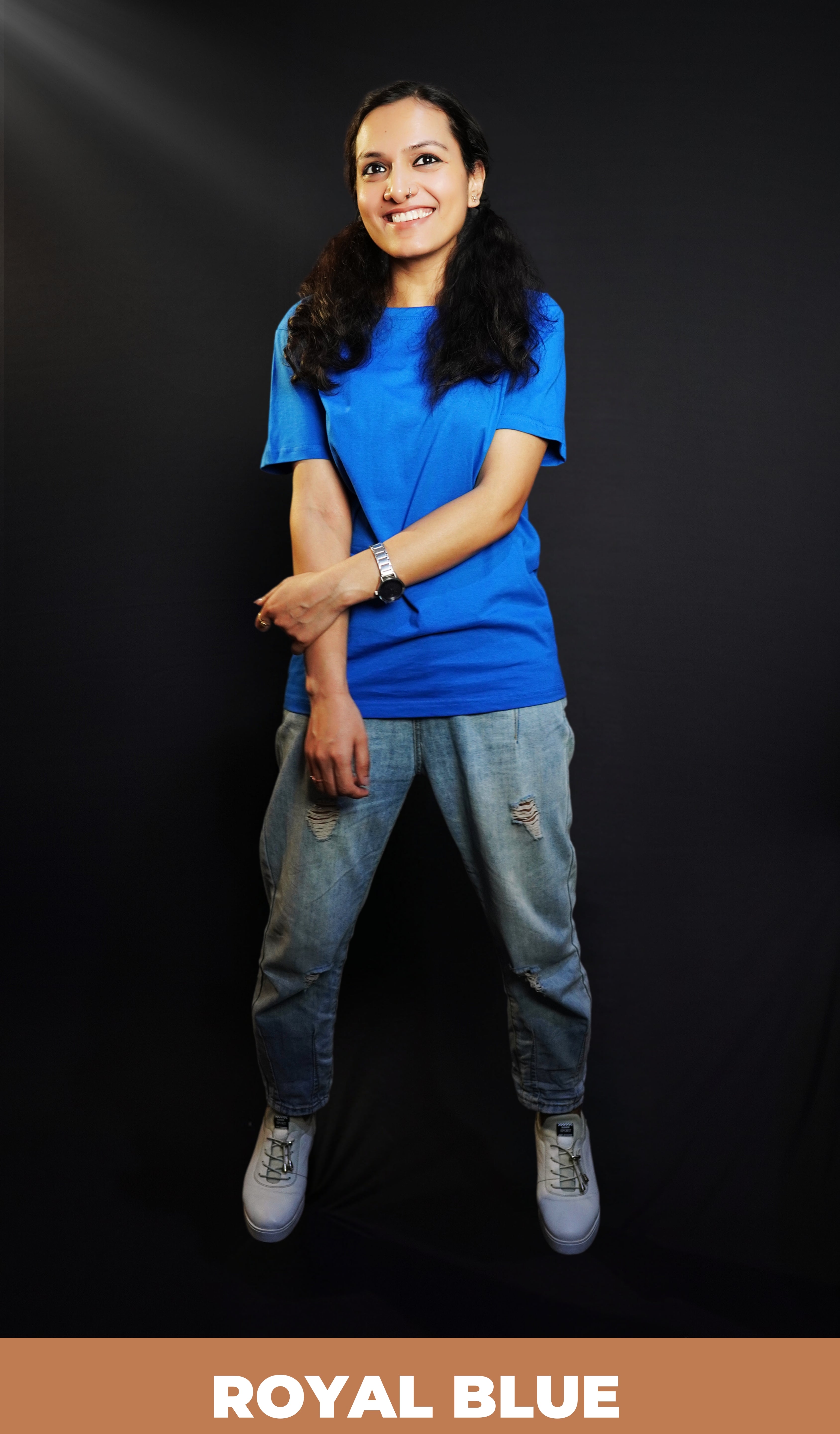 A woman laughing happily with her hand grabbing her forearm, wearing a round neck long length stretchable royal blue t-shirt, showcasing a trendy modern look-Muselot