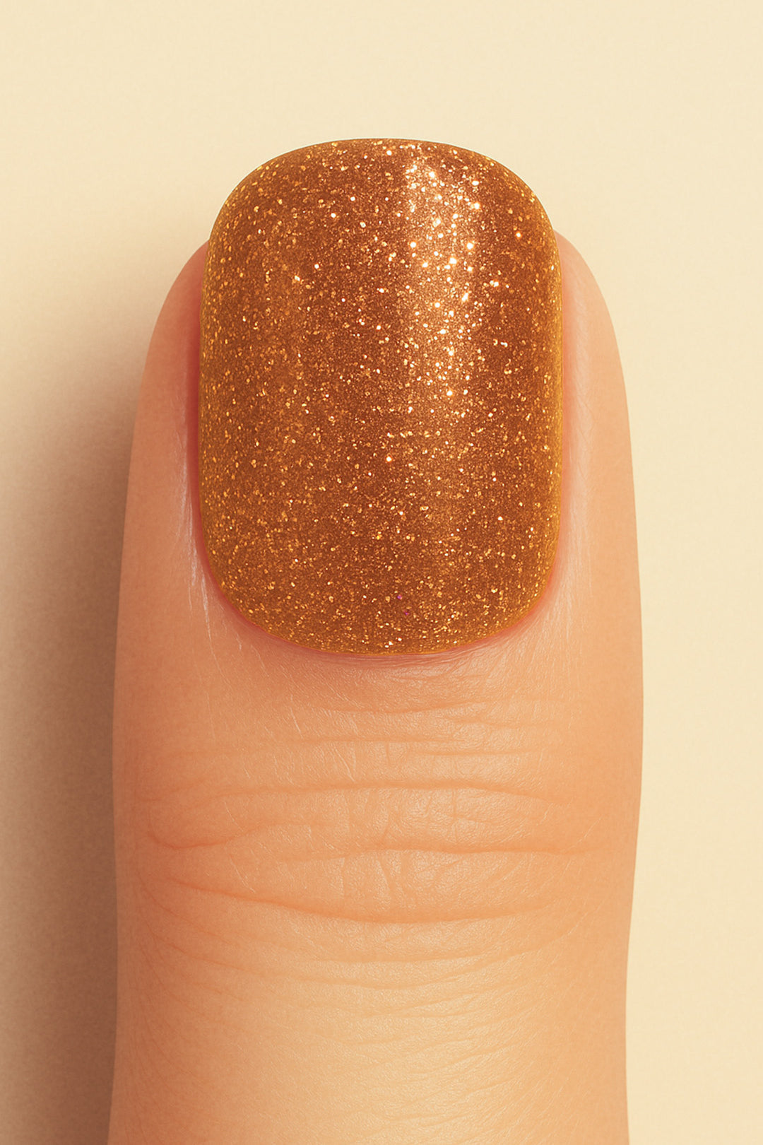 A close-up shot of a model’s finger wearing Warm Gold Glitter nail stickies, showcasing the dazzling golden shade packed with fine glitter particles, highlighting the sparkle and glam of solid glitter nail art with a smooth, glossy finish – Muselot.