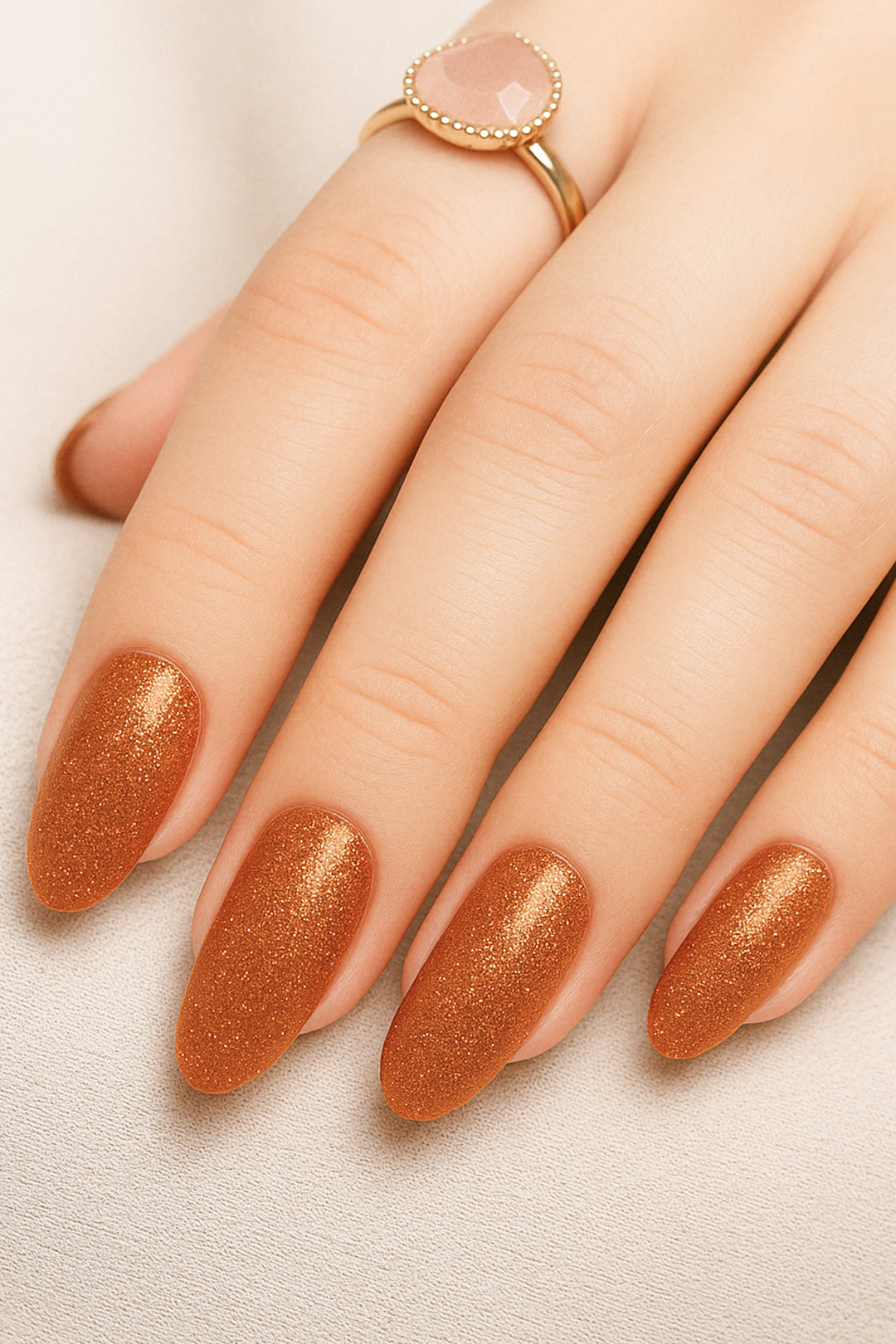 A shot of a model’s hand wearing Warm Gold Glitter nail stickies, showcasing the shimmering golden shade with a full glitter finish, highlighting the sparkle and festive charm of bold nail art in a smooth, salon-style look – Muselot.