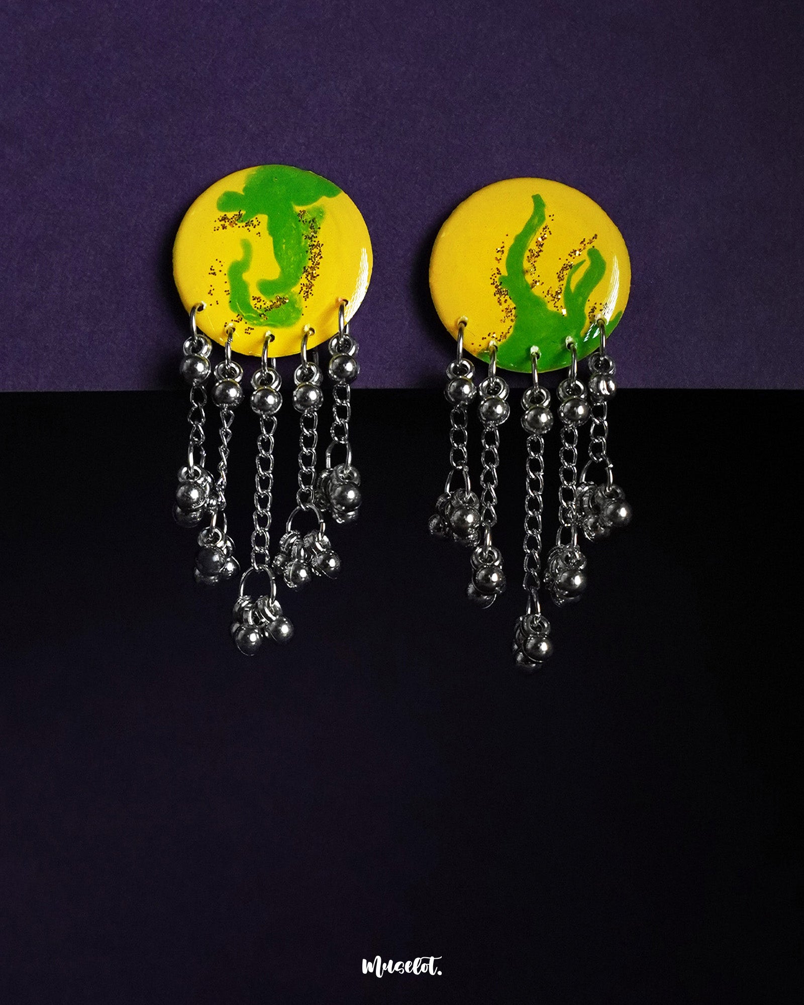 The Zarangi drop chain earrings feature a bold yellow and green hand-painted circular top, with cascading silver-toned chains and ghungroo beads, highlighting the vibrant fusion of color and movement while showcasing handcrafted artistry — Muselot.