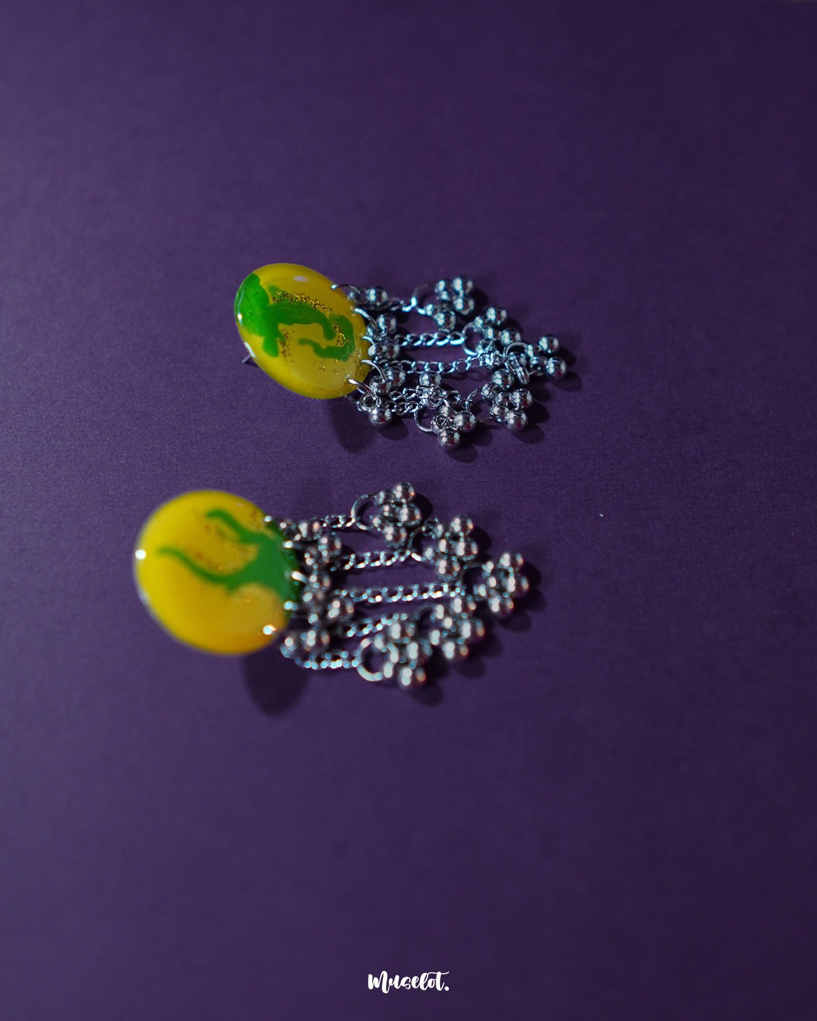 Side view of the Zarangi yellow drop earrings showcasing their round, hand-painted yellow tops with green abstract motifs, and silver-toned chain tassels with jingling ghungroo details — Muselot.