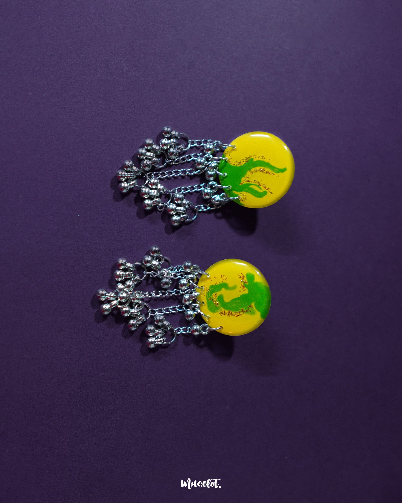Zarangi yellow drop earrings laid flat, highlighting the bold yellow base, green floral detailing, and the silver bead chains that add graceful movement — Muselot.
