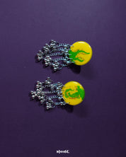 Zarangi yellow drop earrings laid flat, highlighting the bold yellow base, green floral detailing, and the silver bead chains that add graceful movement — Muselot.