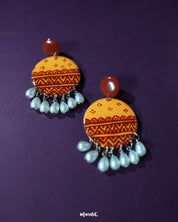 Zardozi traditional handmade earrings featuring circular mustard yellow bases detailed with rust geometric patterns and finished with pearl bead danglers, showcasing rich artisanal charm — Muselot.