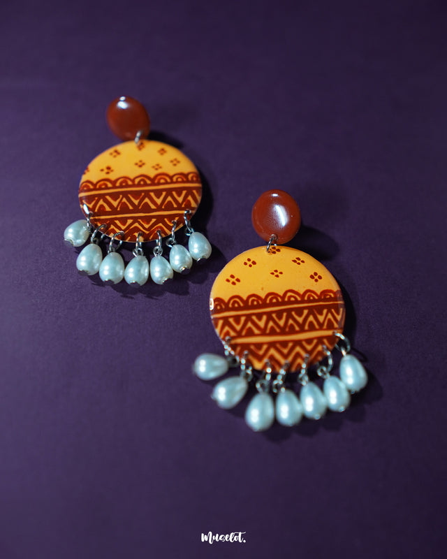Zardozi traditional handmade earrings featuring circular mustard yellow bases detailed with rust geometric patterns and finished with pearl bead danglers, showcasing rich artisanal charm — Muselot.