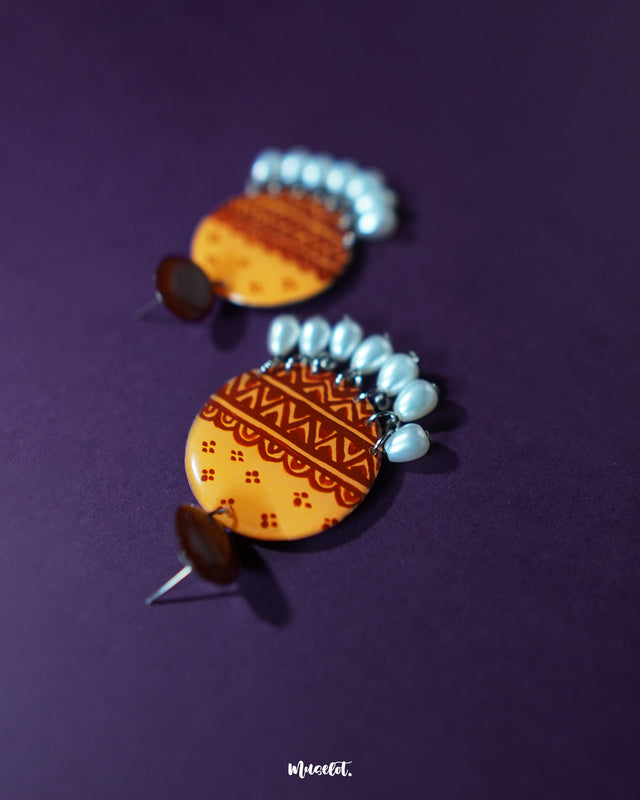 Close-up of Zardozi traditional handmade earrings showcasing detailed embroidery in mustard and rust tones, with delicate white bead drops, highlighting the intricate craftsmanship and rich cultural design — Muselot.