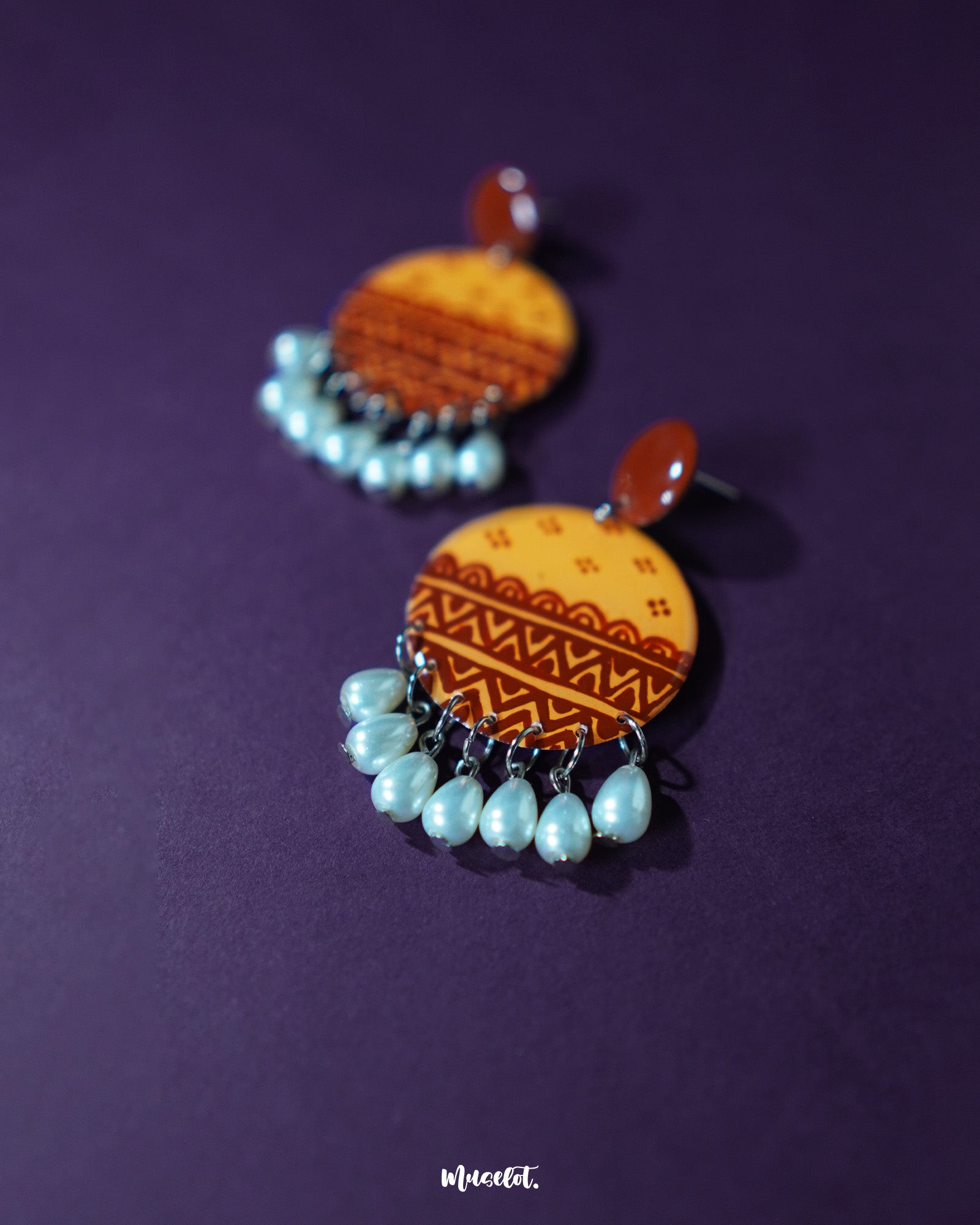 A close-up of Zardozi traditional handmade earrings featuring detailed embroidery in muted reds and golds, highlighting the fine artisanal work and showcasing timeless ethnic charm — Muselot.