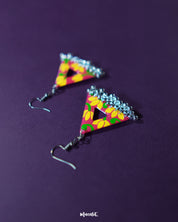 Triangle-shaped floral earrings with bright yellow and pink hand-painted flowers on a red base, highlighting their bold colors and showcasing dangling silver jhumki charms against a rich purple background — Muselot.