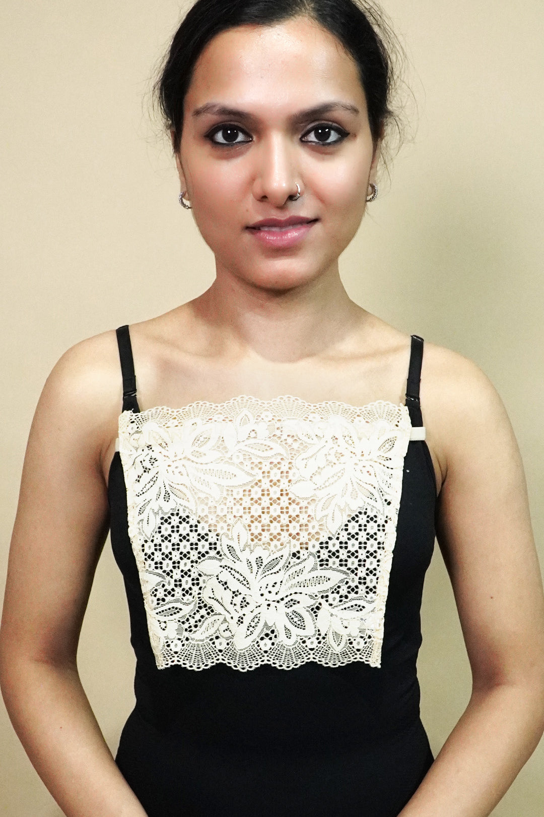 front view of woman holding beige lace camisole insert to show width and shape on beige background, showcasing lace mock camisole coverage for deep neckline tops – muselot