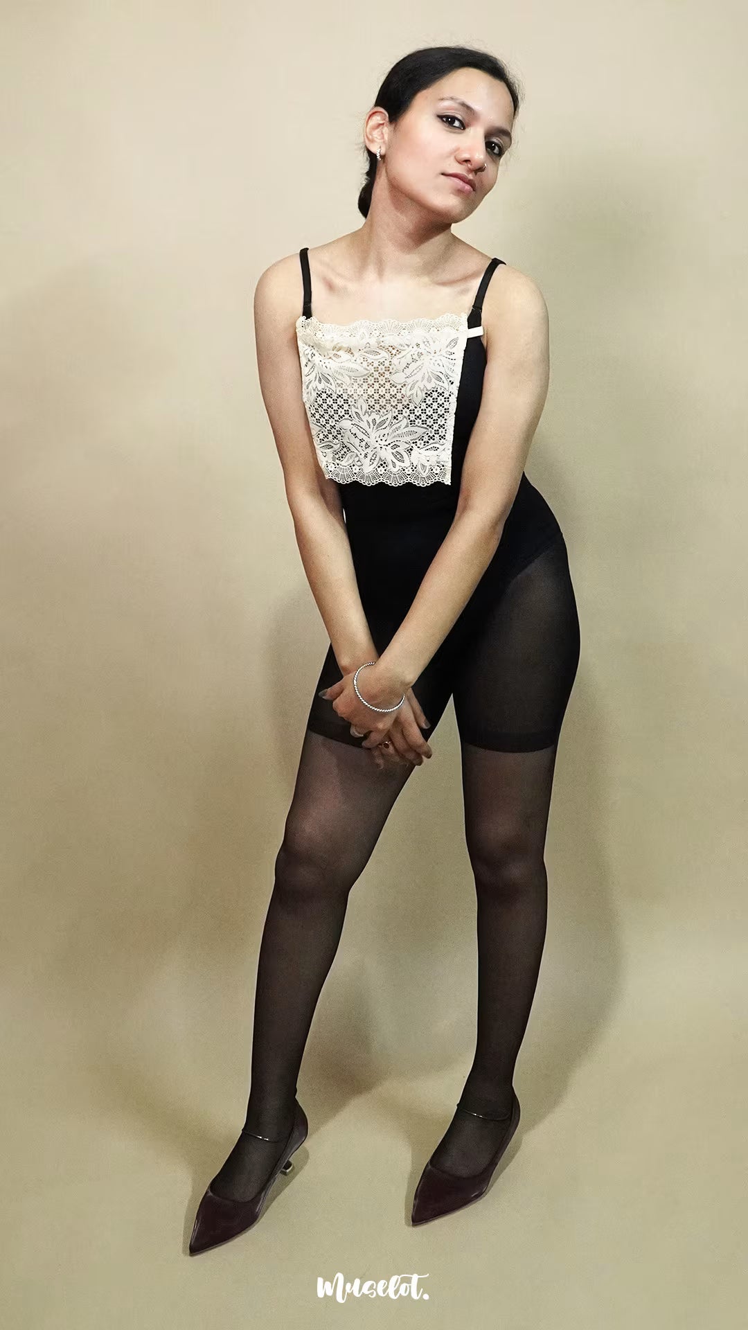 full body view of woman wearing beige lace camisole insert over black outfit on beige background, showcasing clean neckline coverage with wide lace mock camisole for deep neck styling – muselot