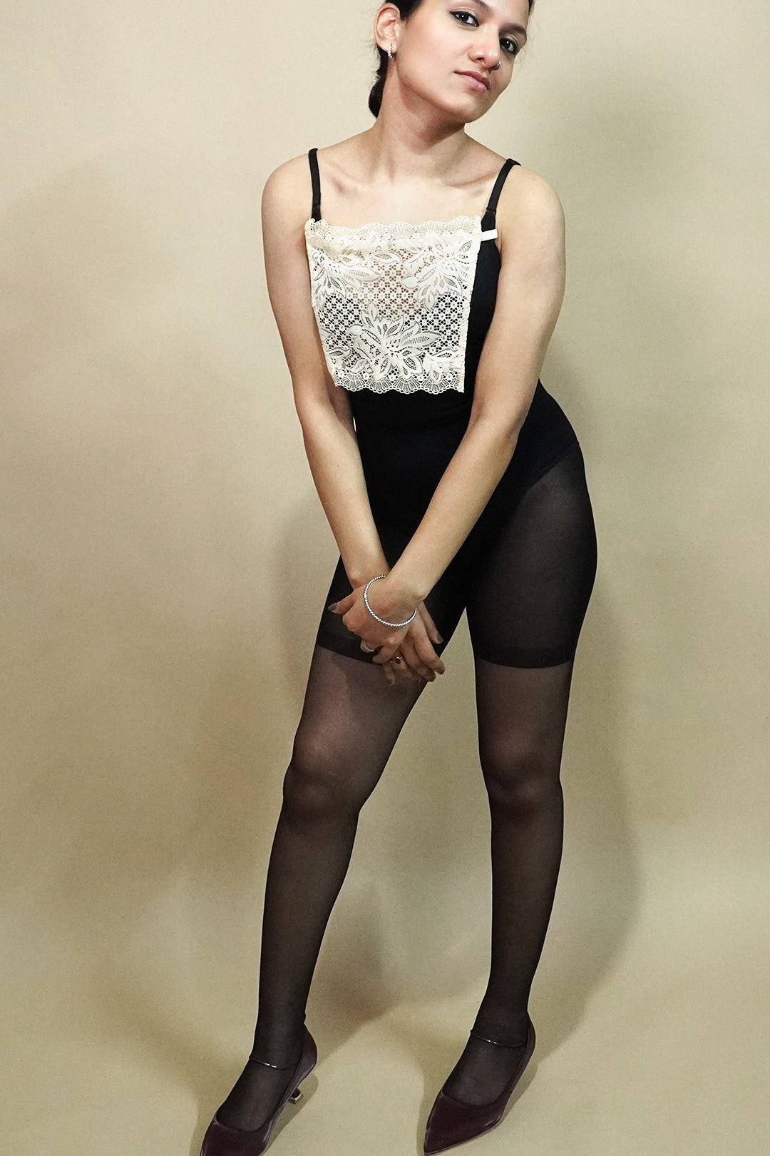full body view of woman wearing beige lace camisole insert over black outfit on beige background, showcasing clean neckline coverage with wide lace mock camisole for deep neck styling – muselot