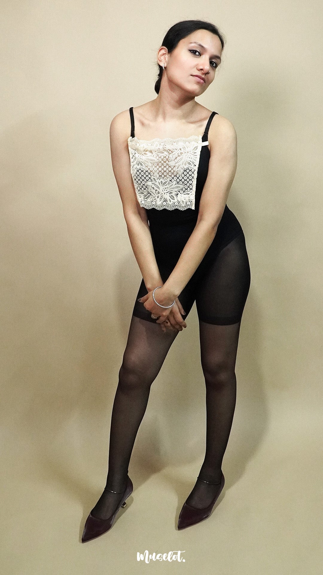 full body view of woman wearing beige lace camisole insert over black outfit on beige background, showcasing clean neckline coverage with wide lace mock camisole for deep neck styling – muselot