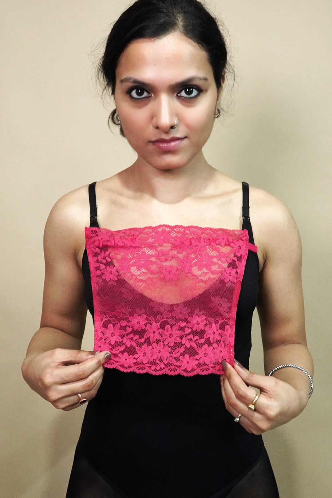 front view of woman holding dark pink lace camisole insert to show width and coverage on beige background, highlighting deep neck cover styling with lace mock camisole – muselot