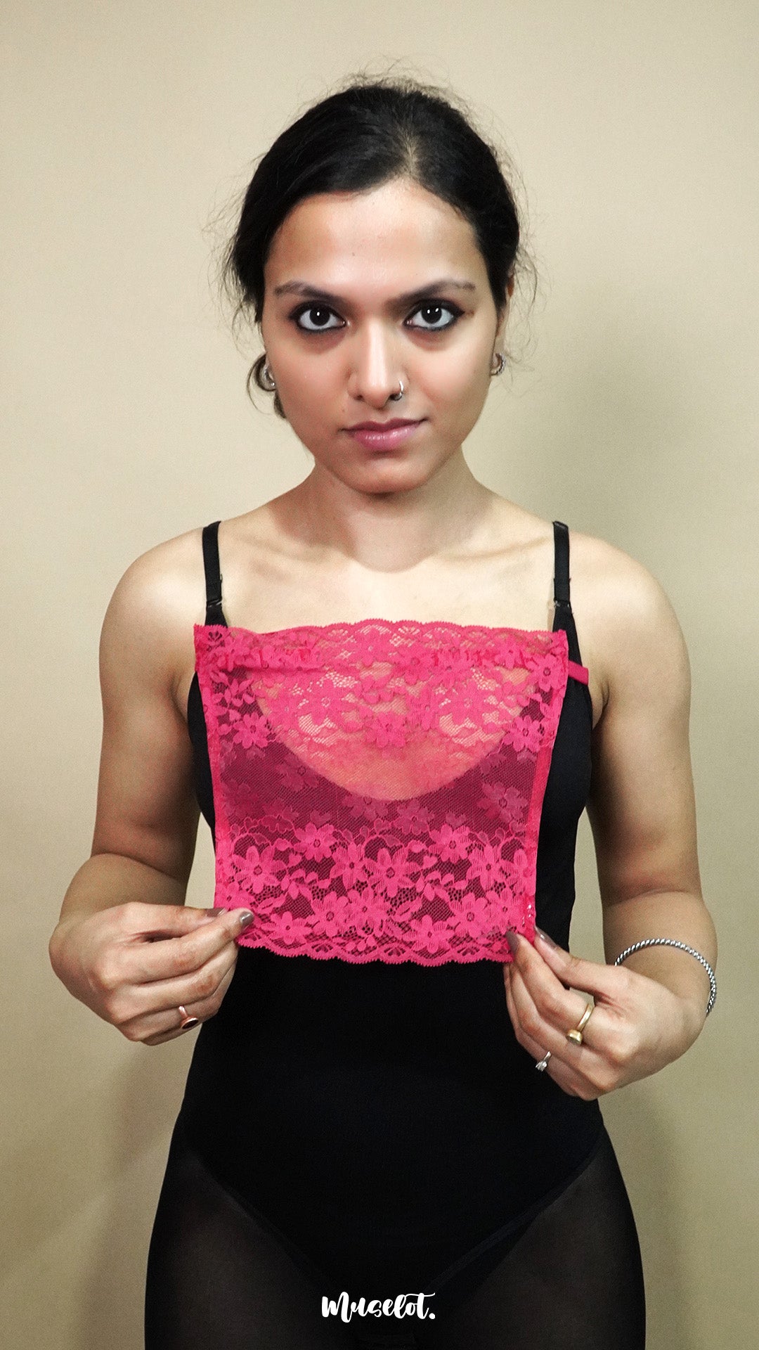 front view of woman holding dark pink lace camisole insert to show width and coverage on beige background, highlighting deep neck cover styling with lace mock camisole – muselot