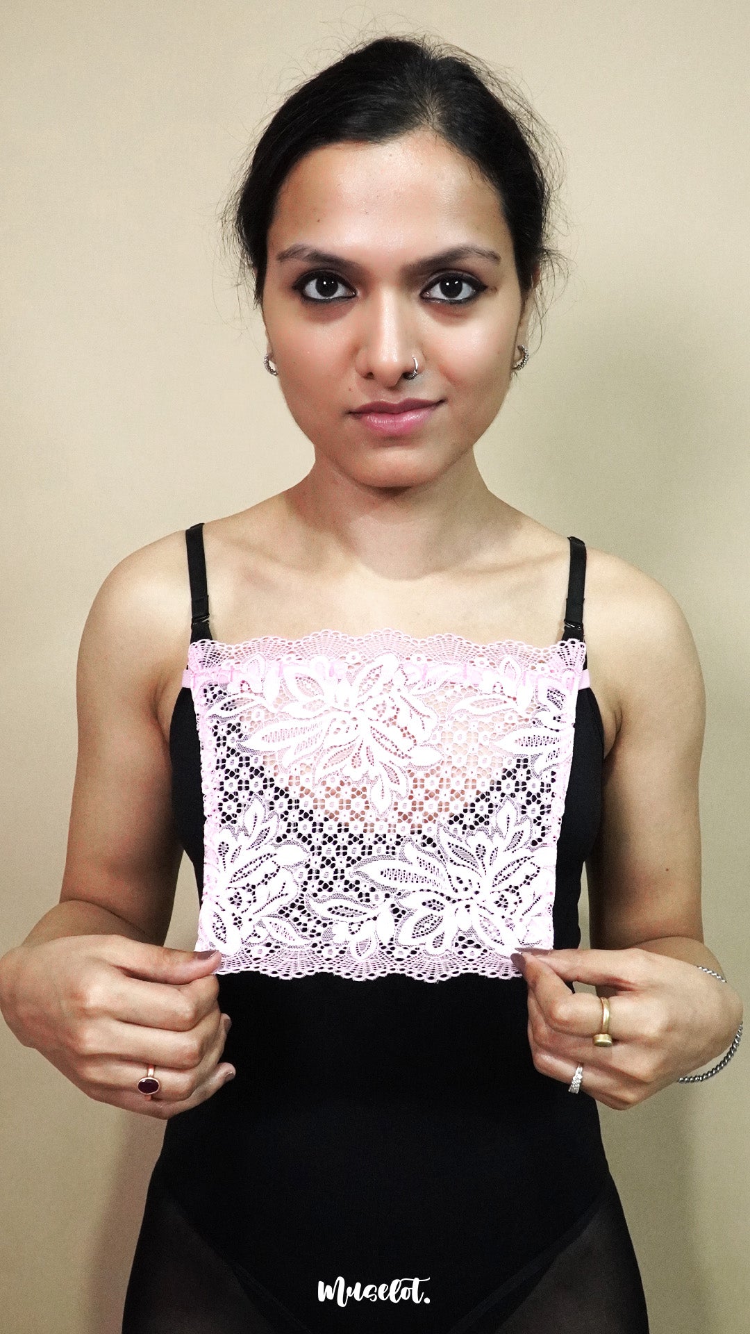 front view of woman holding baby pink lace camisole insert to display width and shape on beige background, showcasing lace mock camisole styling for covering deep neck tops – muselot