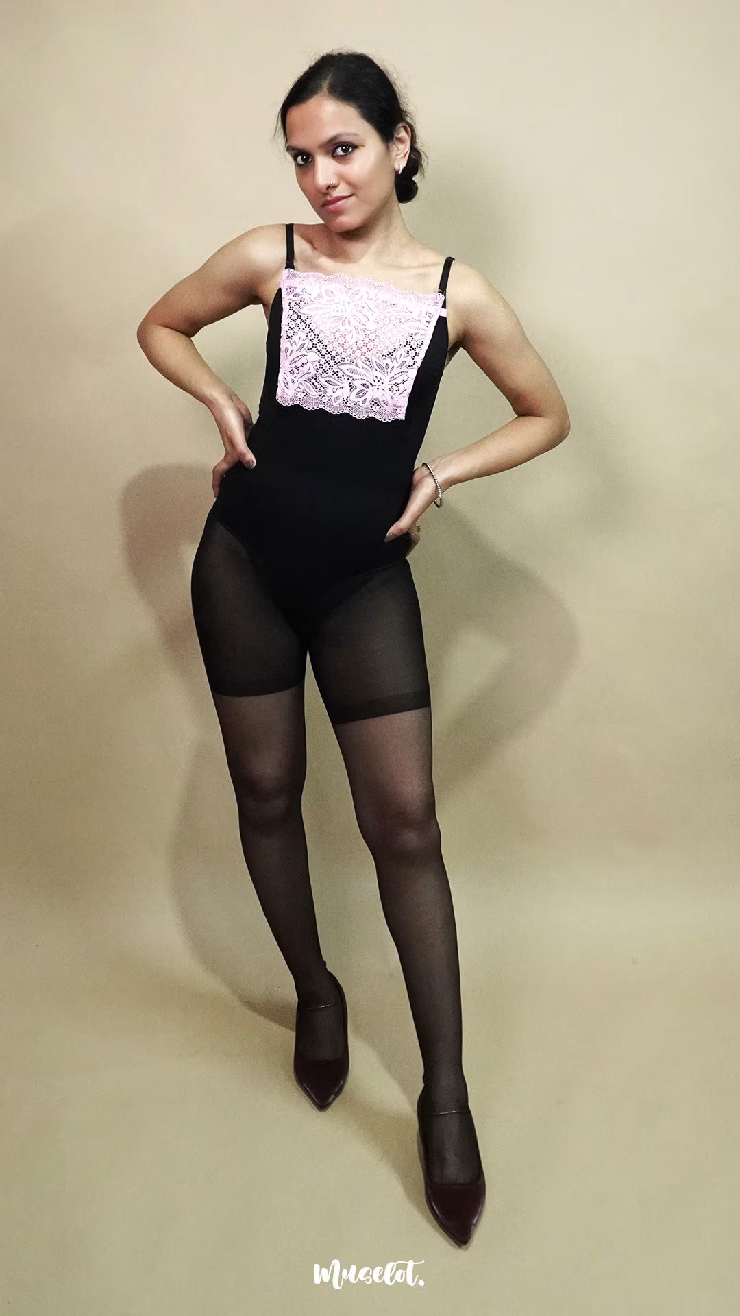 full body view of woman wearing baby pink lace camisole insert over black dress on beige background, showcasing neat neckline coverage with wide lace mock camisole for deep neck outfits – muselot
